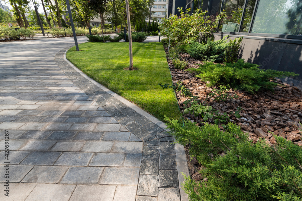 outdoor granite tiles, a flowerbed with juniper and thujas and wooden oak bark in a flowerbed in landscape design outdoor granite tiles, a flowerbed with juniper and thujas and wooden oak bark in a flowerbed in landscape design