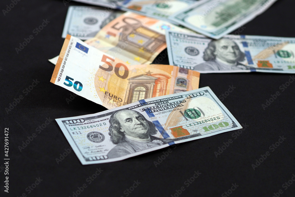 50 euro and 100 usd banknotes are standing side by side on a black background, 50 euro and 100 usd banknotes are standing side by side on a black background,