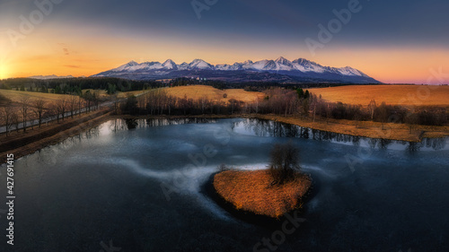 frozen pond with an island in the middle at sunset, golden hour