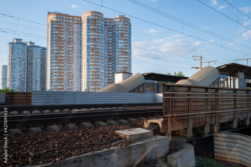 metal fencing and corrugated sheds along the railway in a residential area near high-rise buildings