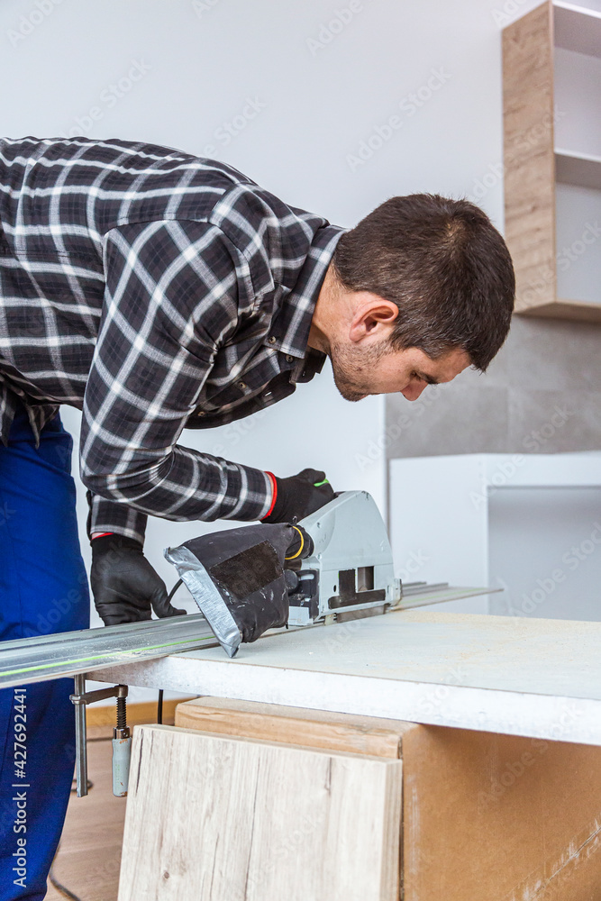 A carpenter cutting a wooden board on the floor of the room A carpenter cutting a wooden board on the floor of the room