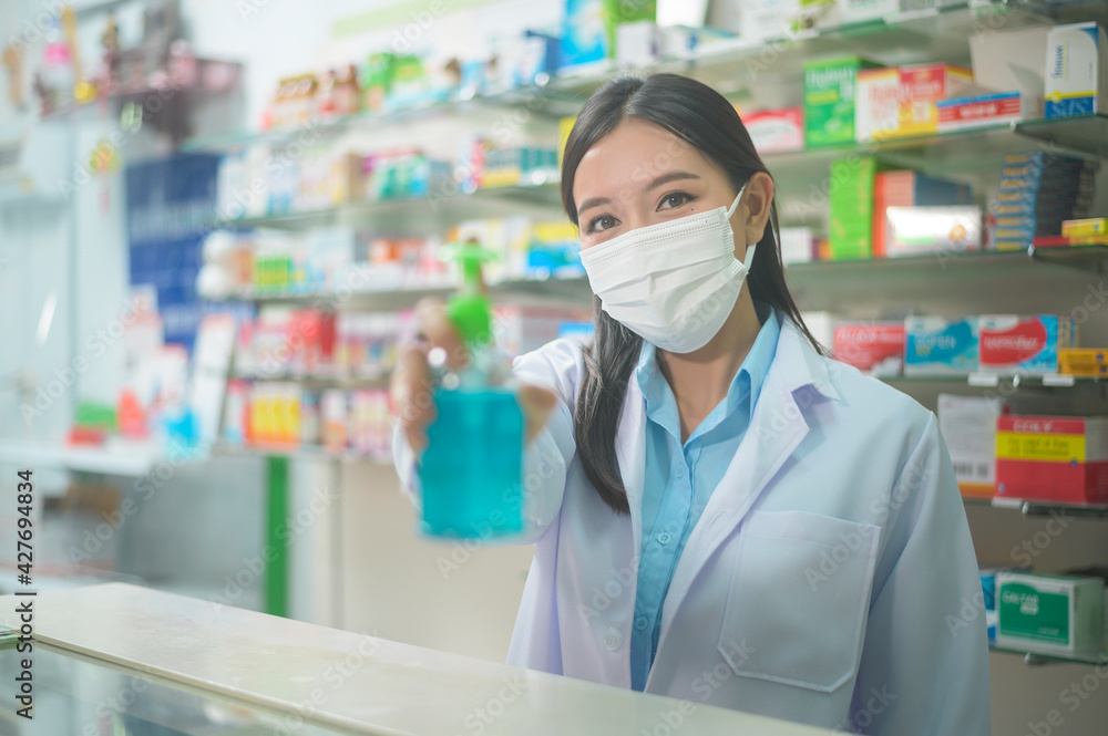 Portrait of asian woman pharmacist wearing a surgical mask using alcohol gel in a modern pharmacy drugstore, covid-19 and pandemic concept. Portrait of asian woman pharmacist wearing a surgical mask using alcohol gel in a modern pharmacy drugstore, covid-19 and pandemic concept.