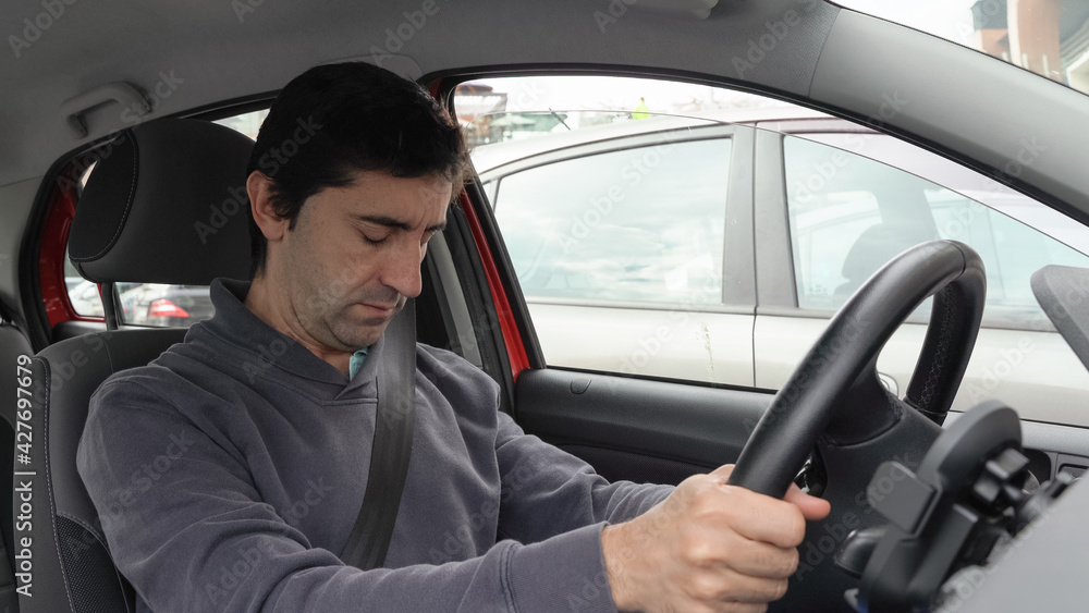 Young man falling asleep while holding steering wheel inside car. Traffic jam, risk of accident concepts Young man falling asleep while holding steering wheel inside car. Traffic jam, risk of accident concepts