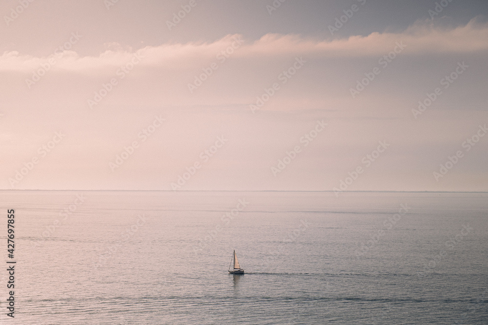 Dreamy boat on the ocean sailing in the sunset. Dreamy sunset background image