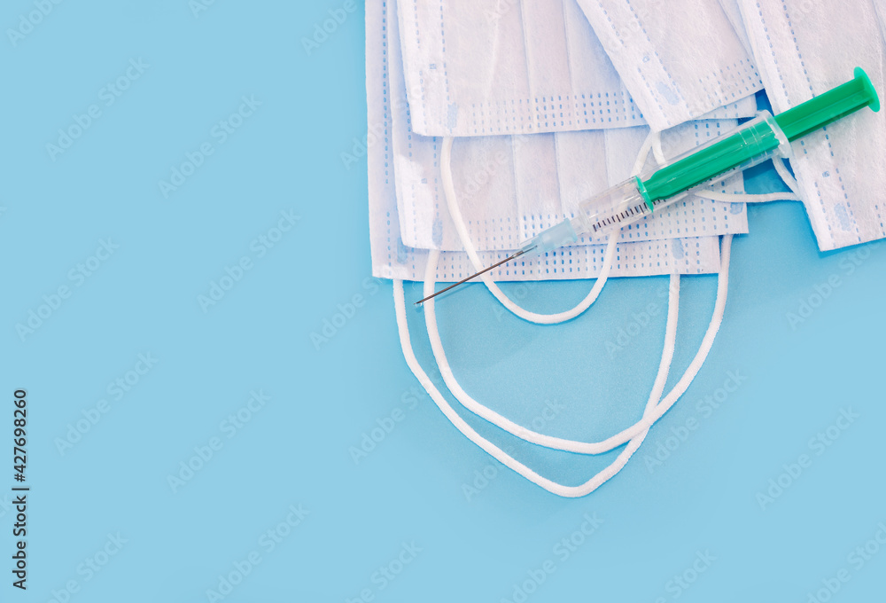 Syringe with vaccine and medical masks and on a blue background. Syringe with vaccine and medical masks and on a blue background.