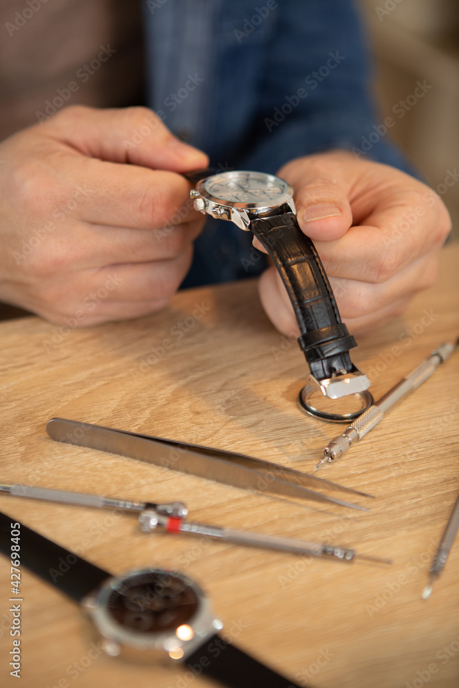 watchmaker in his workshop repairing a wrist watch watchmaker in his workshop repairing a wrist watch