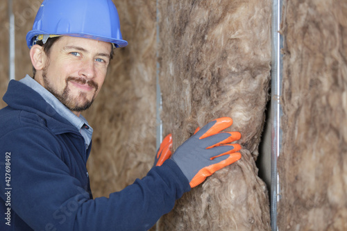 Canvas Print worker in protective gloves insulating rock wool insulation