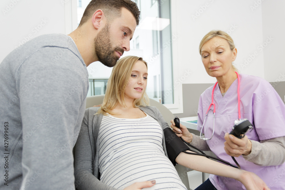 nurse measuring blood pressure of pregnant woman with husband present nurse measuring blood pressure of pregnant woman with husband present