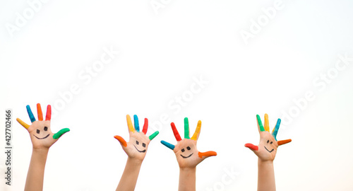 Banner view of children hands in colorful paint with funny smile face isolated on white background