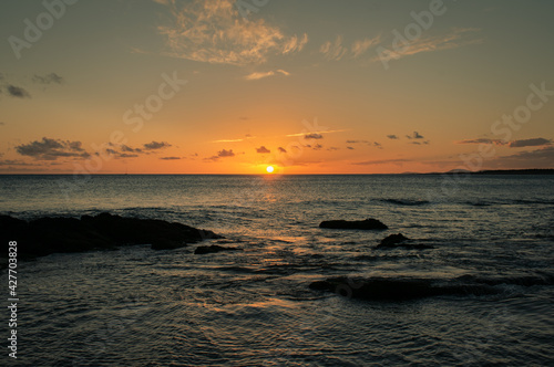 sunset on the beach with the sun falling over the water