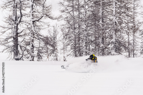 Mountain snowmobile riders ride on the slopes