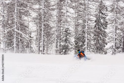 Mountain snowmobile riders ride on the slopes