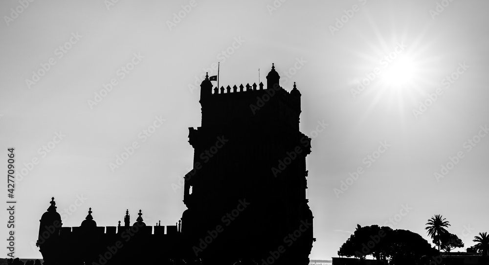 Silhouette of the Belem Tower tower of Saint Vincent with a sun star in the background in Belem, Lisbon, Portugal