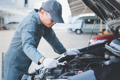 Mechanic with scan tool diagnosing car in open hood. Auto mechanic working. Repair service.