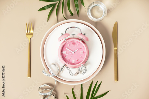 Foto Composition with cutlery, plate, measuring tape and alarm clock on color background