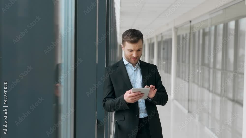 Handsome adult man with tablet meditating in glass corridor Handsome adult man with tablet meditating in glass corridor