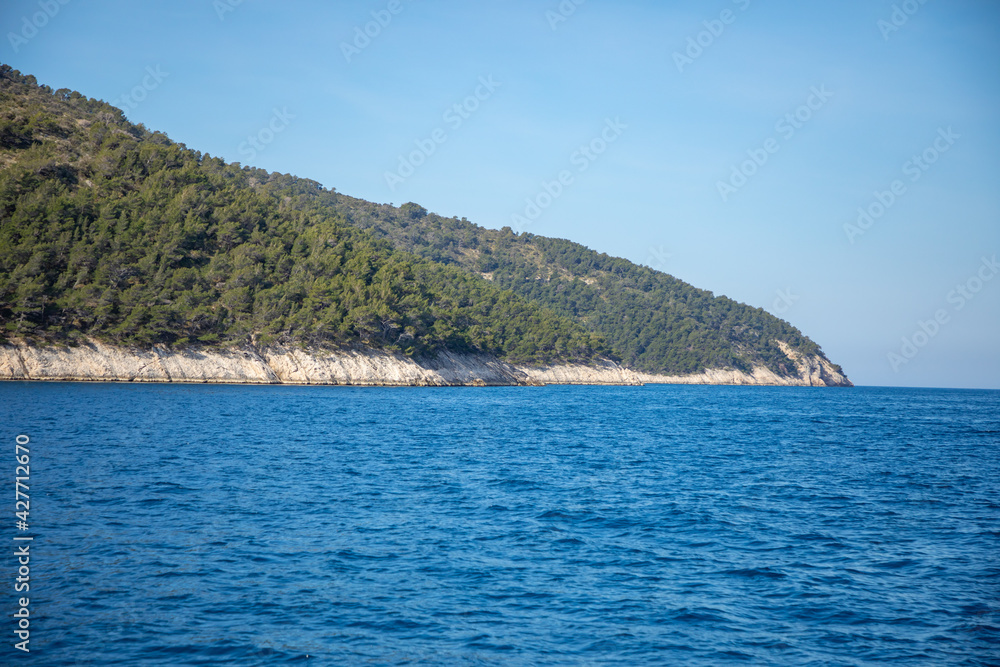 View from water of rocky shore of island in Croatia