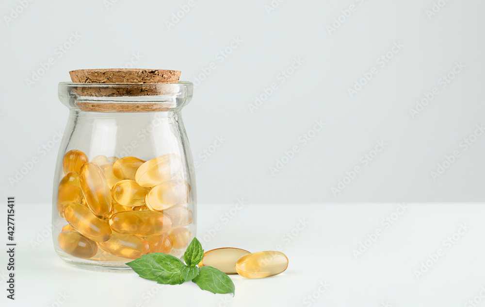 jar with omega 3 capsules and mint leaf on gray background jar with omega 3 capsules and mint leaf on gray background