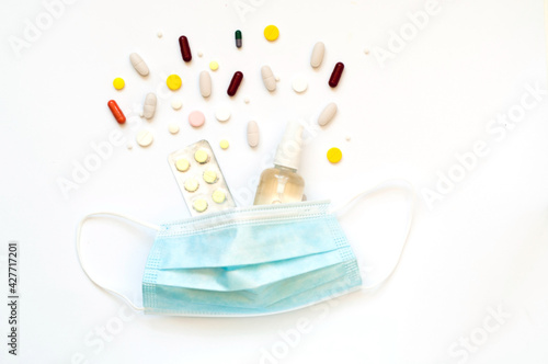 Medical protective mask and multicolored medical pills on white background. Treatment of coronavirus symptoms or Prevent Coronavirus. Copy space. © Nataliia