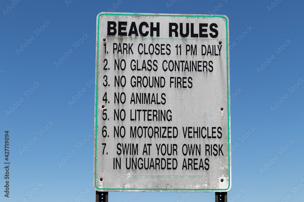 Beach Rules sign against a stark, cloudless blue sky.