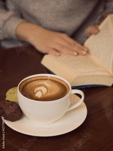 Woman reading a book and drink coffee, Still life with a Cup of coffee, cookies and a book. The atmosphere of a cozy interior Breakfast at home or in a cafe. cappuccino . woman read a book 