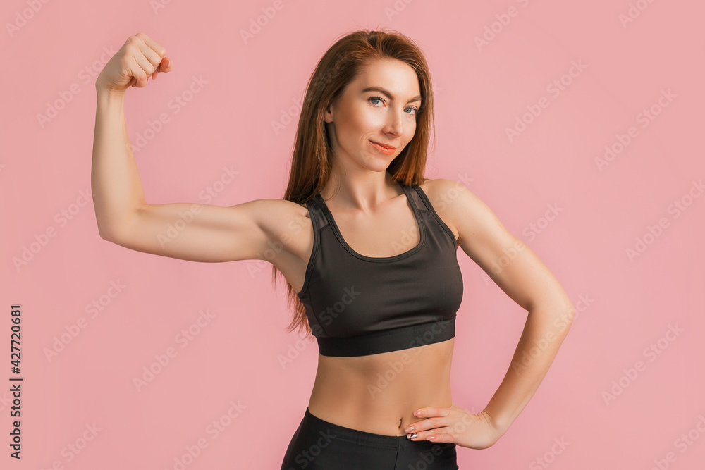 Fitness girl smiling in black sportswear on a pink background. Slim woman with a beautiful athletic body and tanned skin Fitness girl smiling in black sportswear on a pink background. Slim woman with a beautiful athletic body and tanned skin