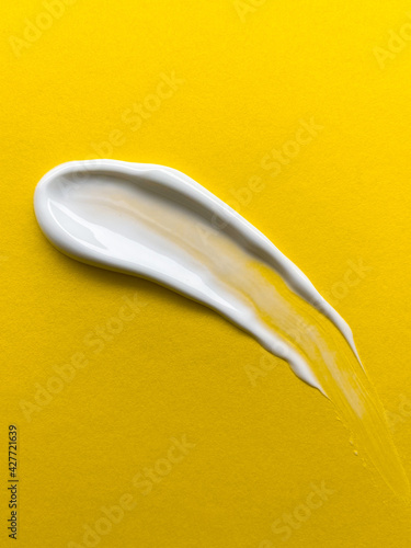Swabs of creamy textures. Strokes of body lotion or hand cream. Smear of skincare cosmetics product. Cosmetology wellness and beauty concept. Isolated on yellow.