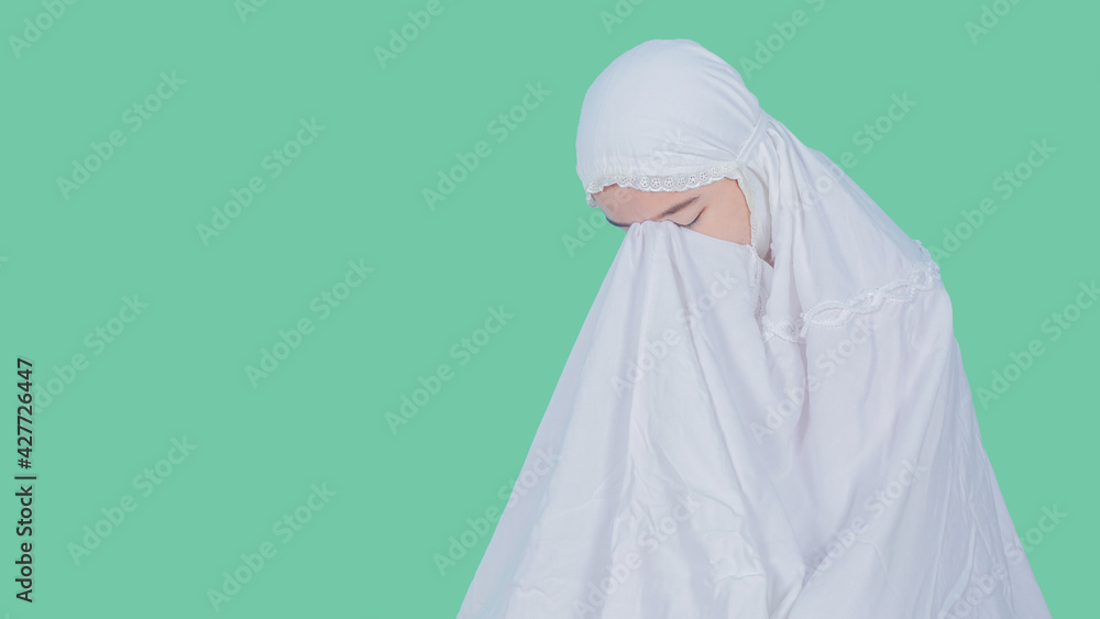 Young Muslim woman praying isolated on color background - ramadan concept