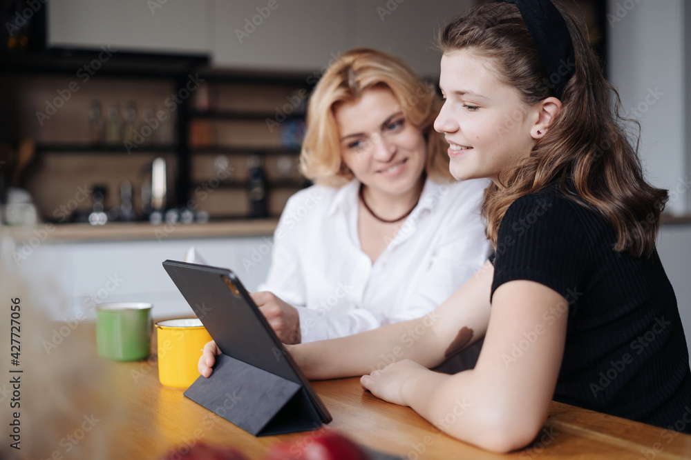 Mother discussing with her daughter teenager while drinking tea in living room at home Mother discussing with her daughter teenager while drinking tea in living room at home