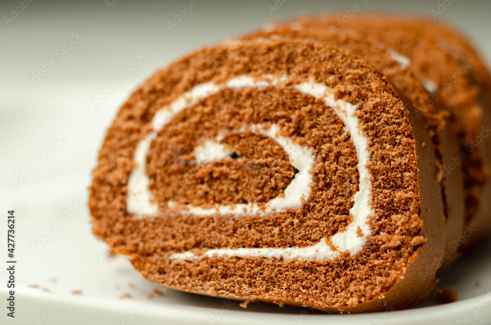 Chocolate sponge roll with a vanilla flavour filling, chocolate swiss roll Chocolate sponge roll with a vanilla flavour filling, chocolate swiss roll