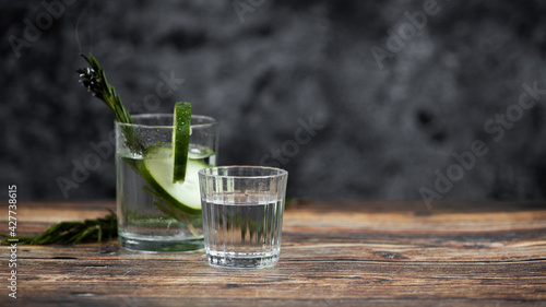 Bebida mexicana de agave mezcal tipo tequila hecha en oaxaca servida en veladora oaxaqueña sobre mesa de madera rústica acompañada de limón y sal de gusano 