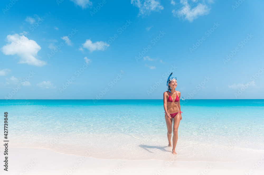 Snorkel bikini woman having fun coming from swimming in cristalline ocean water snorkeling in the Caribbean. Summer beach travel lifestyle.