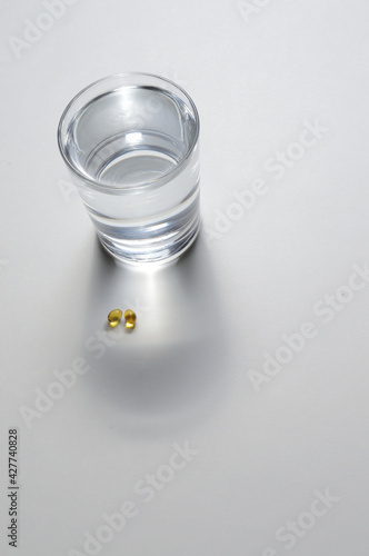 a glass beaker and two yellow tablets with vitamins. close-up.