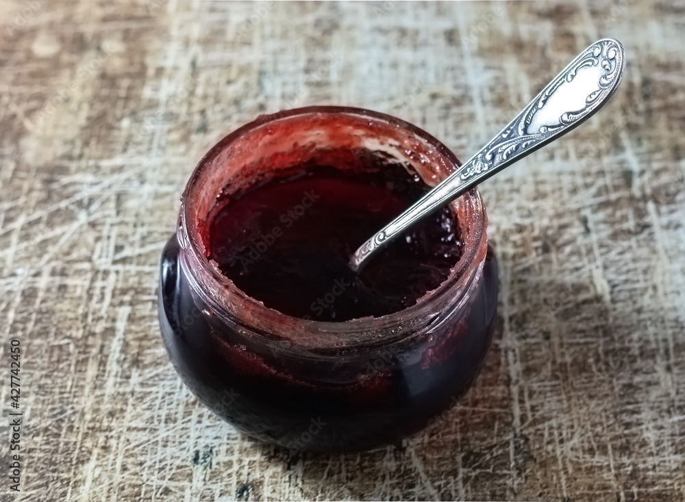 A jar of berry jam or jelly on an old table. Close-up.