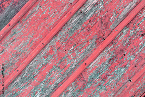 Background from old diagonal boards with peeled red paint with nails