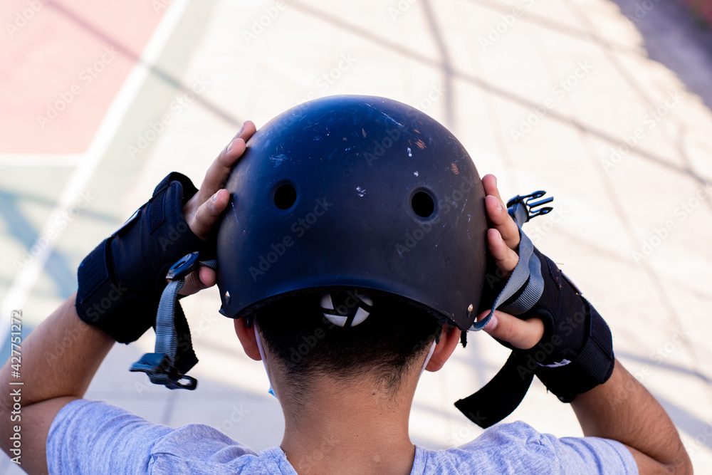 Close-up from behind of a preteen putting on his helmet. Close-up from behind of a preteen putting on his helmet.