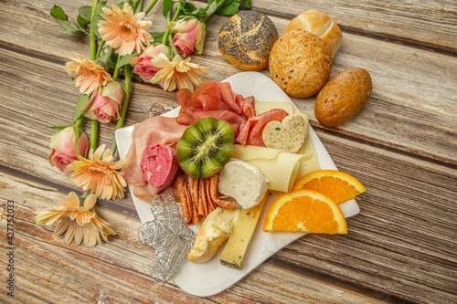 Close-up of an eclectic and healthy breakfast served in a lovely arrangement with flowers on a wooden background	