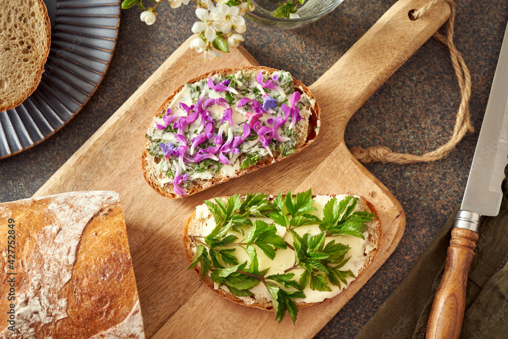 Two slices of bread with wild edible spring plants - young goutweed leaves, purple dead-nettle and lungwort blossoms Two slices of bread with wild edible spring plants - young goutweed leaves, purple dead-nettle and lungwort blossoms