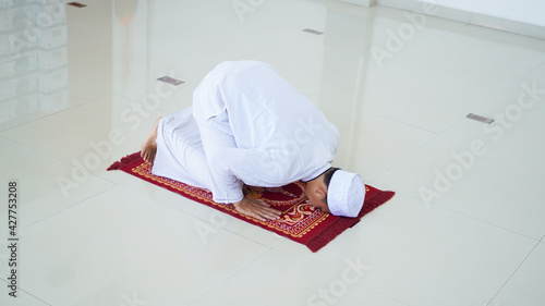 A portrait of an asian muslim man pray at mosque, the pray name is sholat, sujud movement on sholat photo