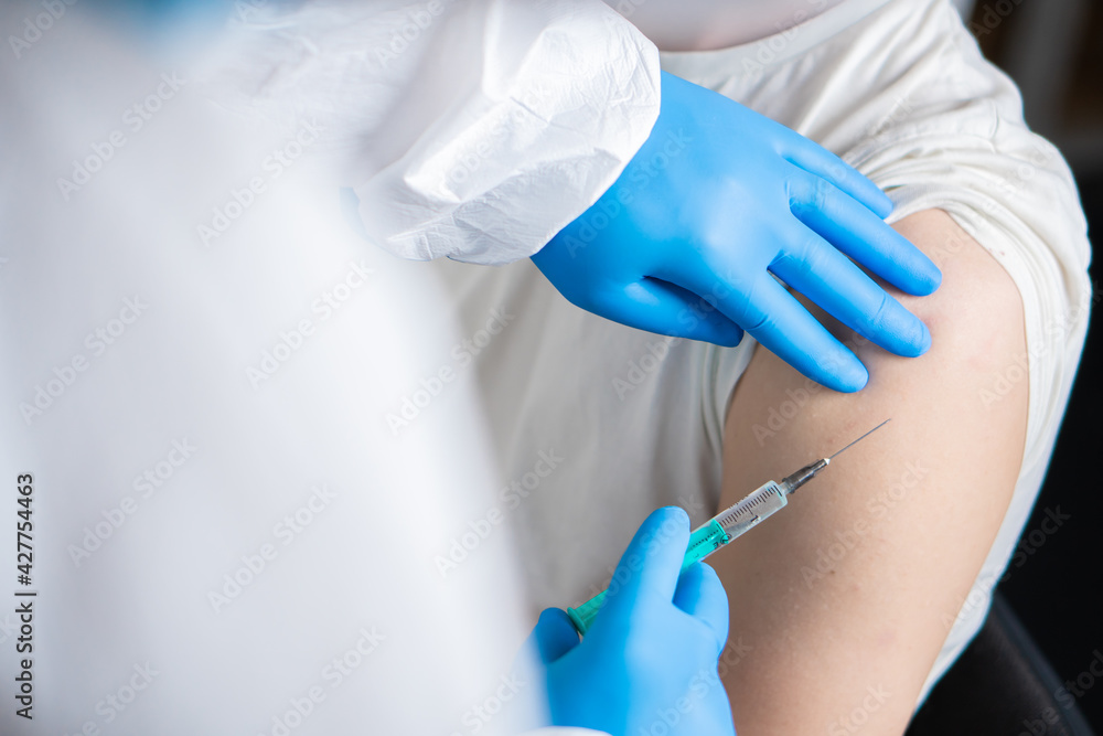 A doctor dressed in a protective suit vaccinates a patient against coronavirus. A doctor dressed in a protective suit vaccinates a patient against coronavirus.