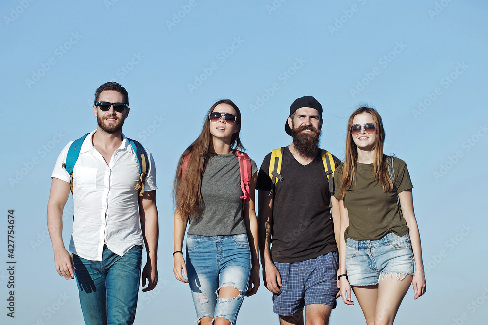 Freinds in jeans and shorts with backpacks walking outdoor. Tourists on nature. Freinds in jeans and shorts with backpacks walking outdoor. Tourists on nature.