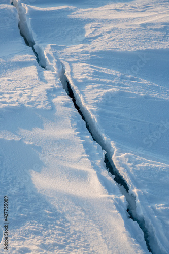 Crack in the ice cover. Snow covered ice. Cracked ice floes on the sea in the Arctic. Polar region.