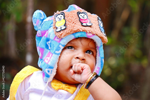 indian baby boy wearing fancy cloth cap with beautiful smile in close up photo