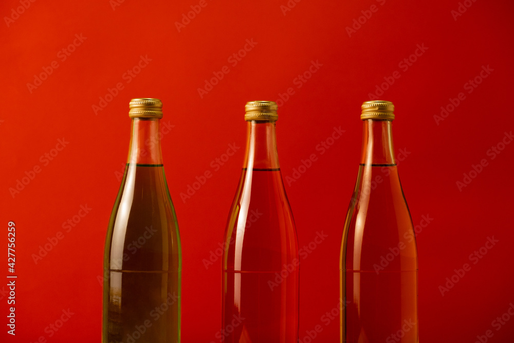 Three glass multi-colored bottles with a drink on a red background Three glass multi-colored bottles with a drink on a red background