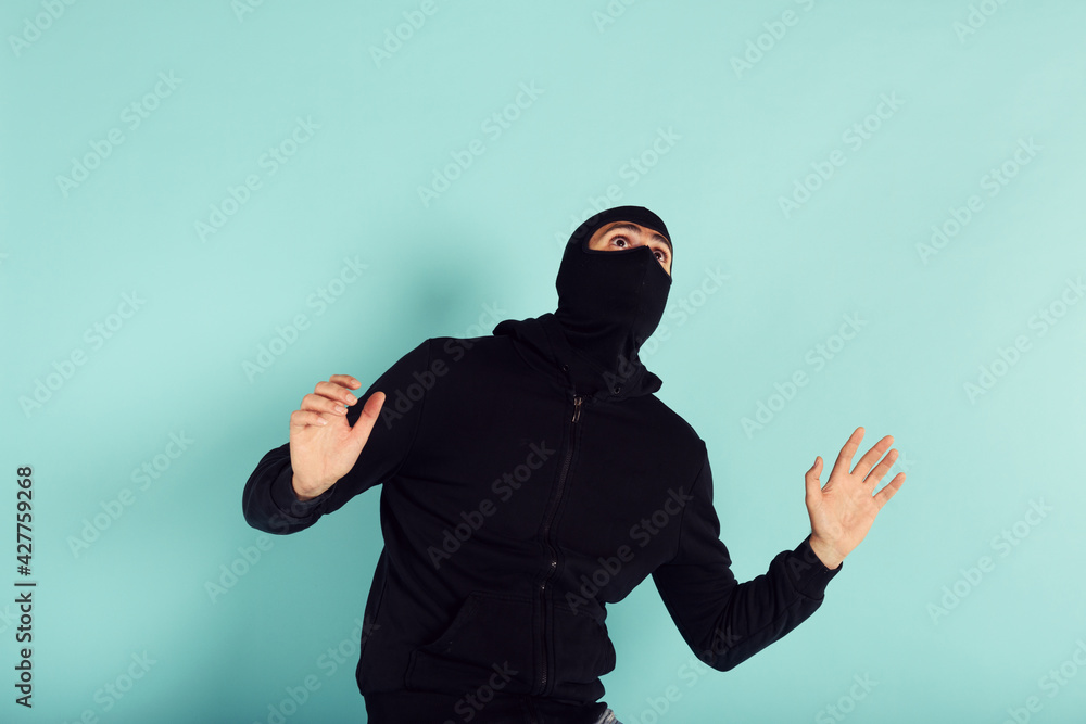 Thief with balaclava was spotted trying to steal in a apartment. Scared expression Thief with balaclava was spotted trying to steal in a apartment. Scared expression
