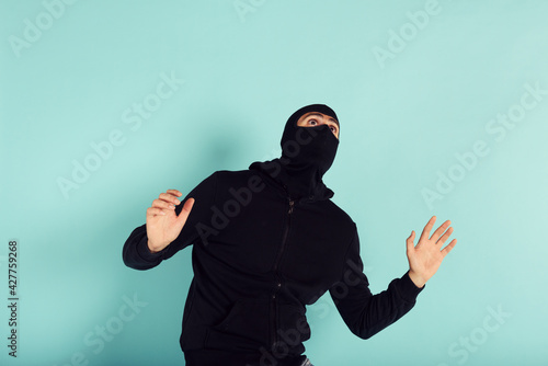 Thief with balaclava was spotted trying to steal in a apartment. Scared expression photo