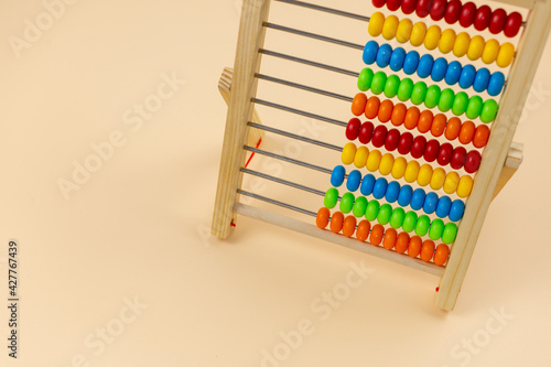 Wooden abacus with beads on beige background. Back to school  games for kindergarten  preschool education.