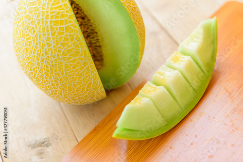 Fresh yellow galia melon on wood plate photo