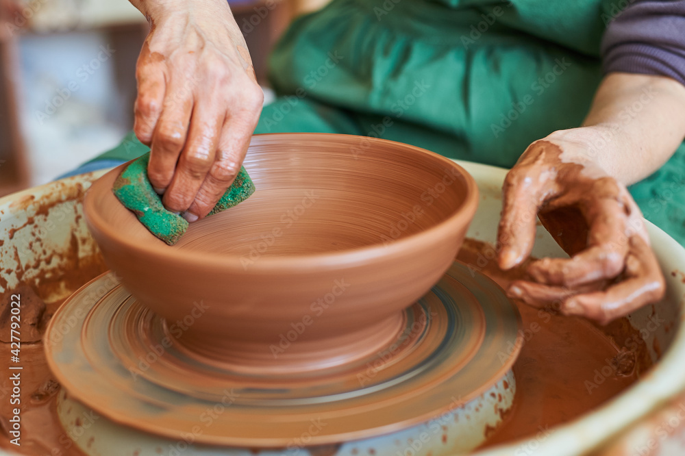 Close-up of the hand of a master potter working on a circle with clay. Master class in the workshop.