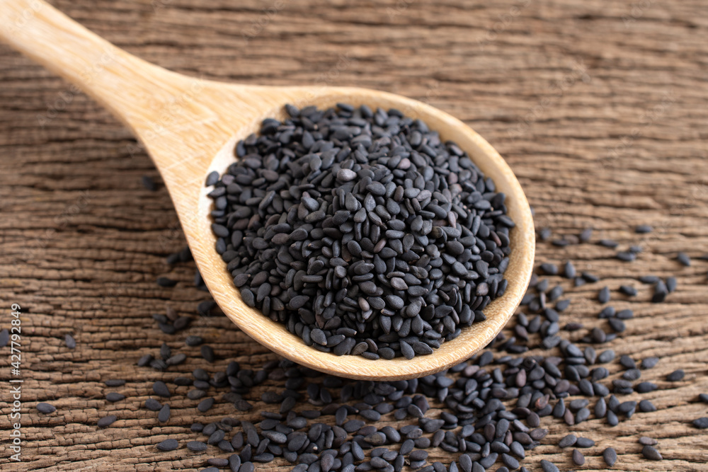 Black sesame (Poppy) in wooden spoon on wooden background,Top view,close up. Black sesame (Poppy) in wooden spoon on wooden background,Top view,close up.